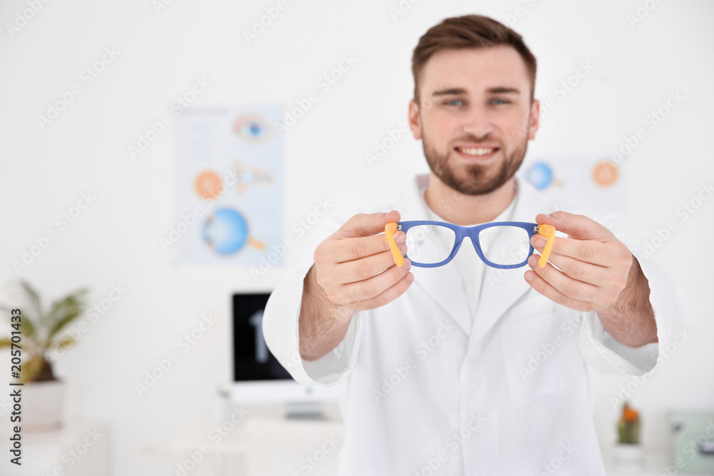 Young ophthalmologist with eyeglasses in clinic Young ophthalmologist with eyeglasses in clinic