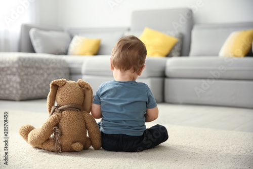 Little boy with toy sitting on floor in living room. Autism concept photo