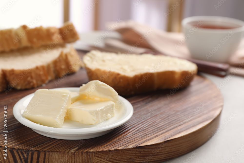 Plate with tasty butter and fresh bread on wooden board Plate with tasty butter and fresh bread on wooden board