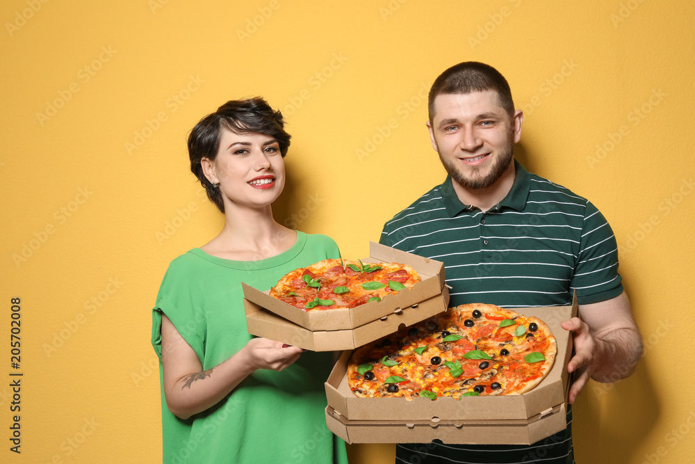Attractive young couple with delicious pizza on color background