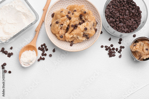 фотография Flat lay composition with cookie dough, chocolate chips and flour on light backg