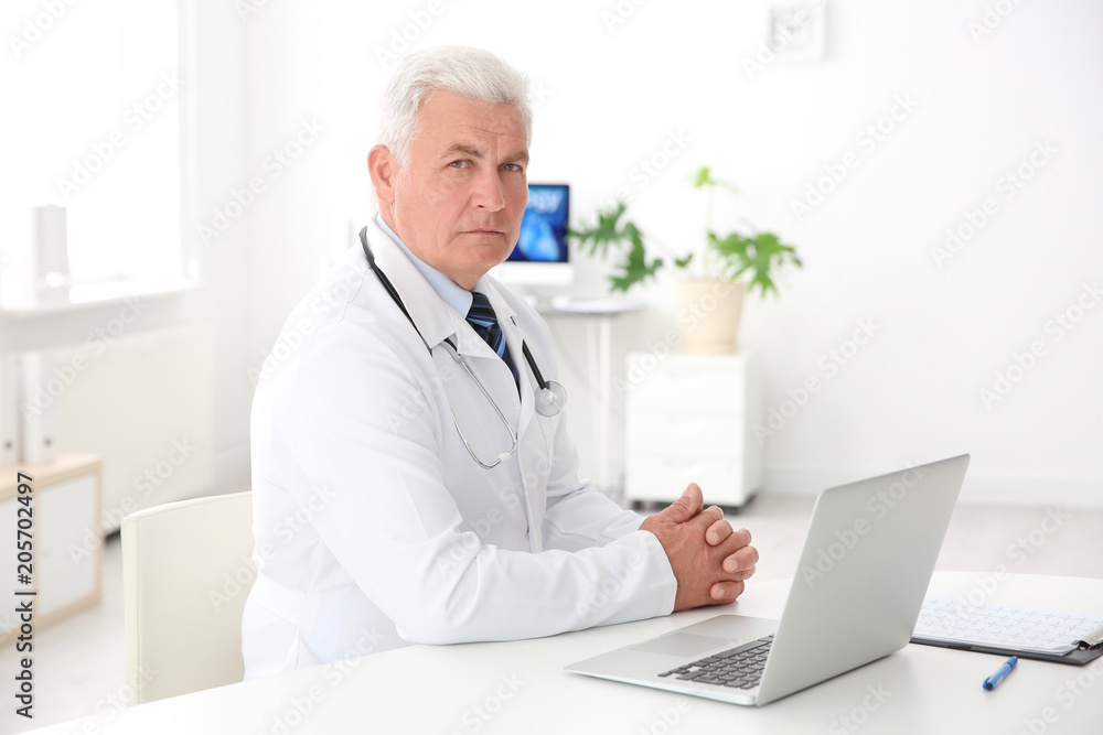 Portrait of male doctor in coat at workplace in clinic. Cardiology center Portrait of male doctor in coat at workplace in clinic. Cardiology center