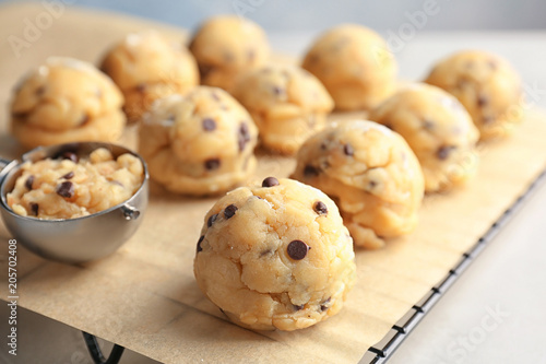 Raw cookie dough with chocolate chips and scoop on parchment paper, closeup