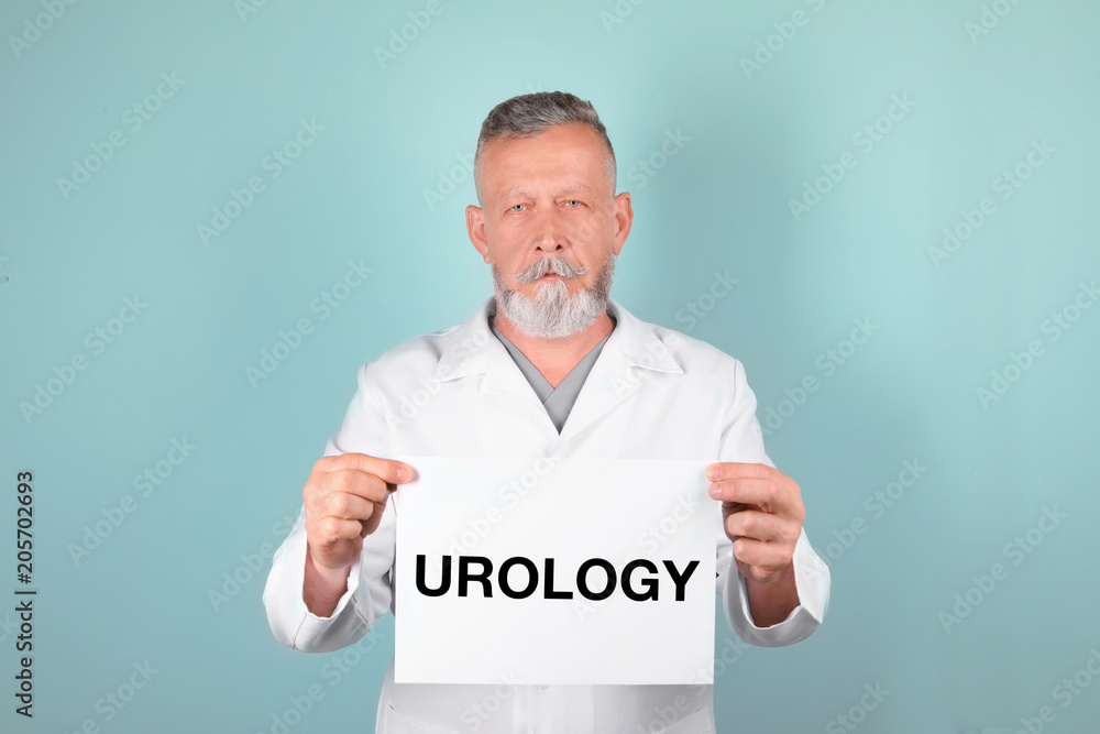 Male doctor holding paper with word UROLOGY on color background Male doctor holding paper with word UROLOGY on color background