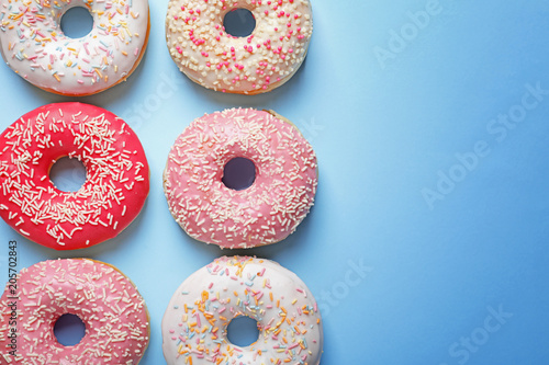 Delicious glazed doughnuts on color background  top view