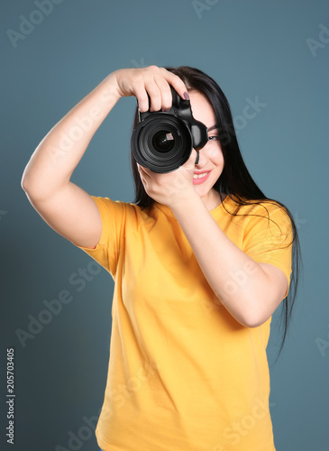 Female photographer with professional camera on color background © New Africa
