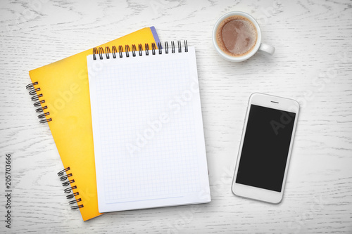 Flat lay composition with notebooks, smartphone and cup of coffee on light background