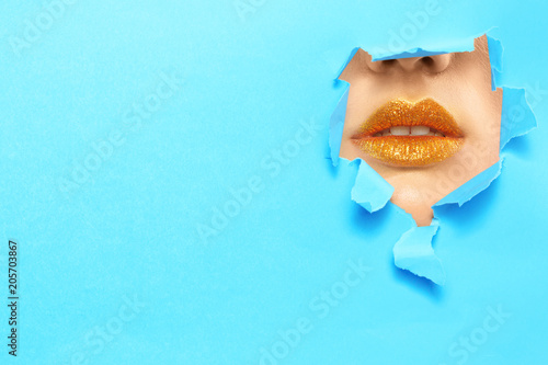 Photography View of beautiful young woman with creative lips makeup through hole in color pa