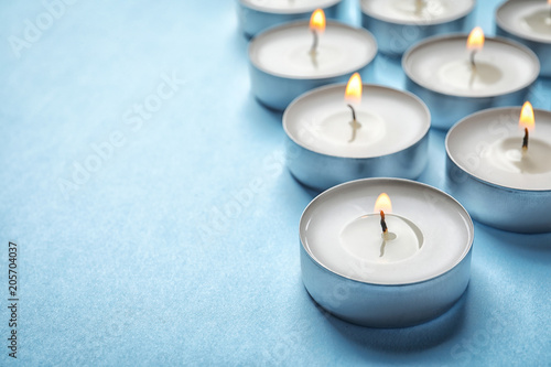 Obraz na plátně Small wax candles burning on color background, closeup