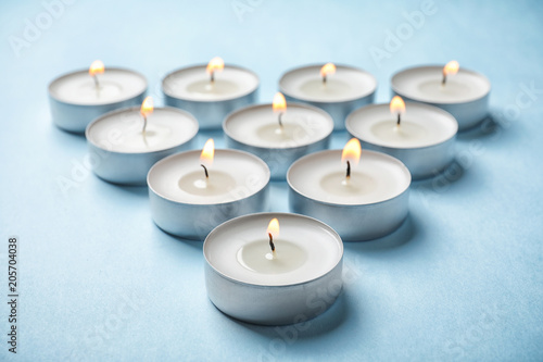 Small wax candles burning on color background
