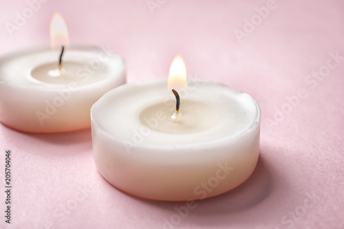 Small wax candles burning on color background, closeup