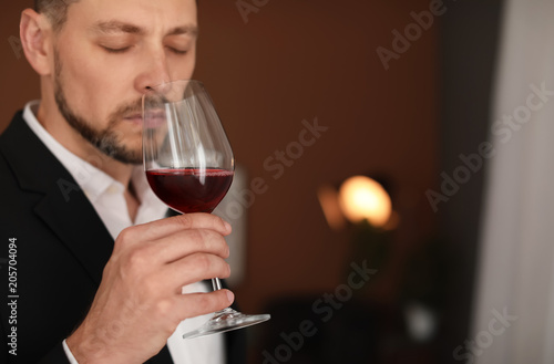 Young man with glass of wine indoors