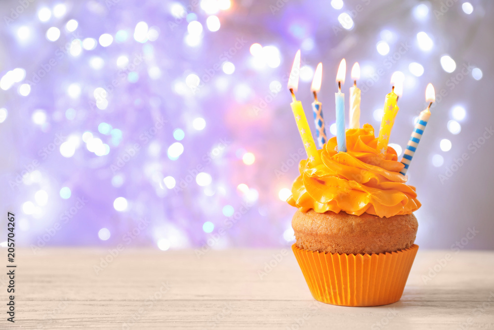 Delicious birthday cupcake with candles on table against blurred background  Stock Photo | Adobe Stock