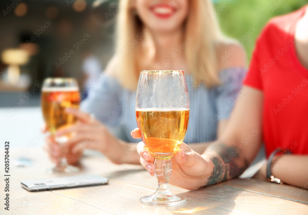 Young women with glasses of cold beer at table Young women with glasses of cold beer at table