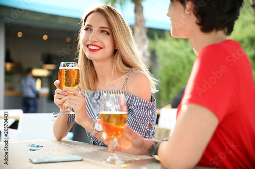 Young women with glasses of cold beer at table