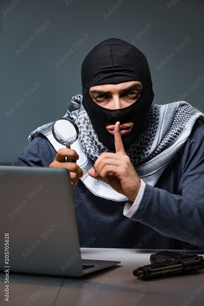 Hacker wearing balaclava mask hacking computer Hacker wearing balaclava mask hacking computer