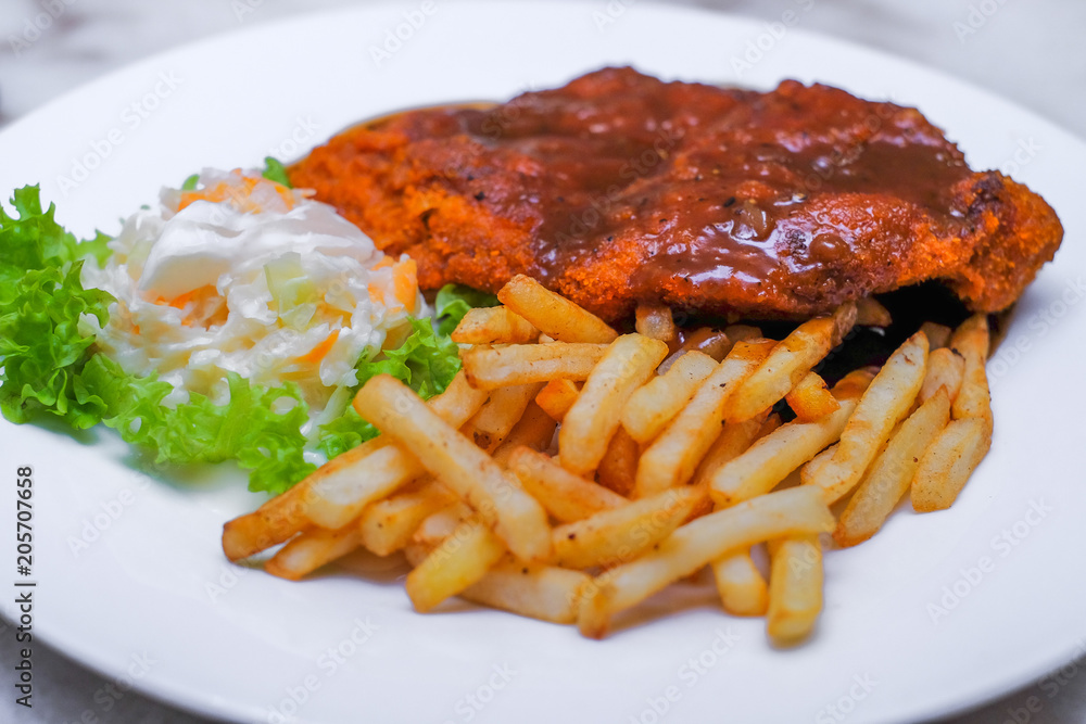 Chicken chop with vegetable and black pepper sauce in plate over dining table Chicken chop with vegetable and black pepper sauce in plate over dining table