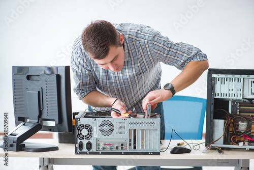 Young technician repairing computer in workshop