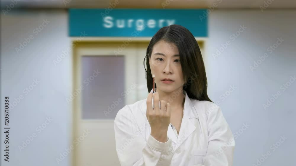 Nurse squeezes syringe outside hospital surgery doors Nurse squeezes syringe outside hospital surgery doors