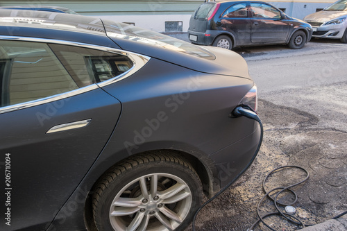 Electric modern car charging with cable power supply plugged on station