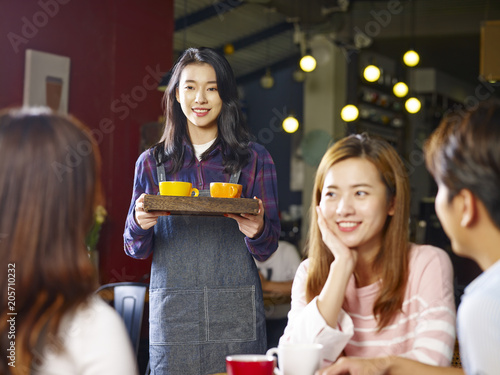 Photography young smiling asian waitress serving coffee to customers