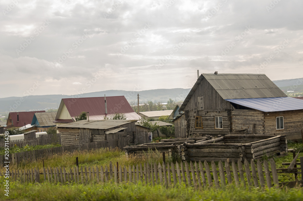 Heavy grey clouds in the cold autumn sky over  village with small houses far away in the mountains and fields. Travelling on the suburb roads. People living