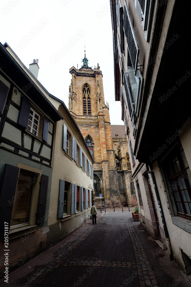 Gorgeous cobbled street in Colmar, Alsace, with the Colmar Cathedral in the background