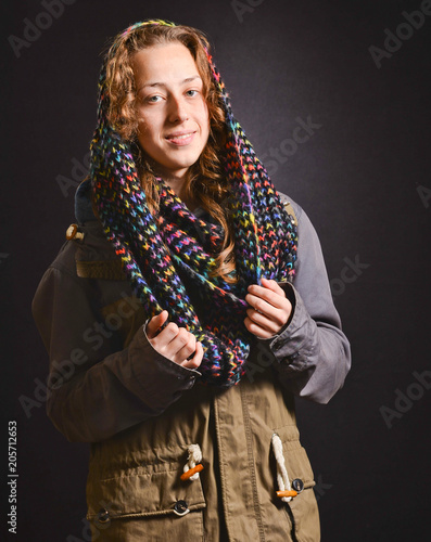 Young happy woman in coat park and scarf on head in studio on a black background. Hipster fashion. Autumn winter clothes. photo