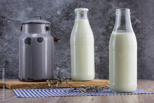 Fresh unpasteurized milk in a old milk jug and two glass bottle
