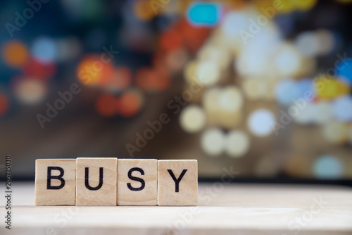 busy word Written In Wooden Cube on wood table with traffic bokeh in background