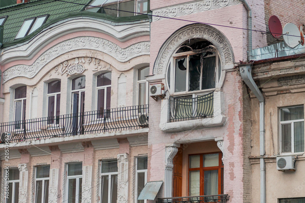 Fototapeta premium Facade of the house after the fire. Blackened from soot wall around the burnt-out apartment. Flames damaged the windows and balconies. Apartment after a fire.