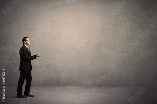 Caucasian businessman standing in front of a grunge  blank wall