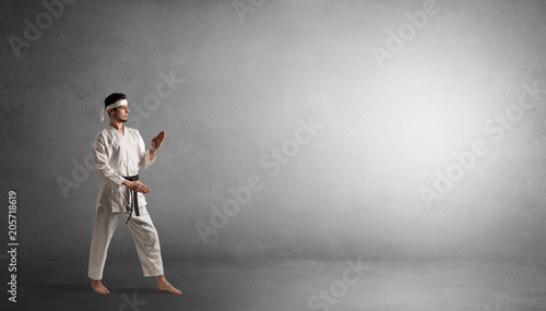 Small karate man fighting in an empty grey copy space