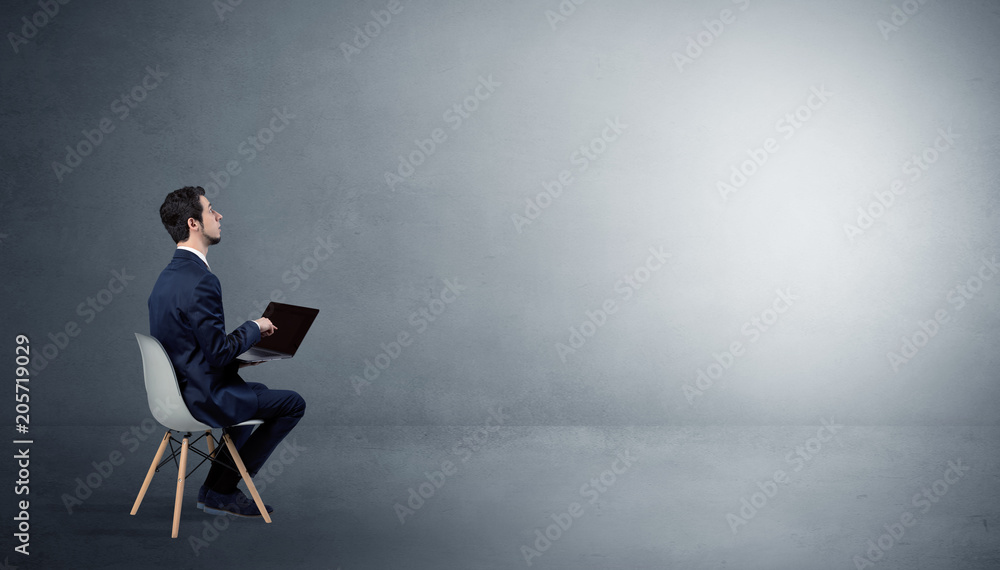 Businessman staying in an empty grey dark room with stuffs on his lap
Businessman staying in an empty grey dark room with stuffs on his lap