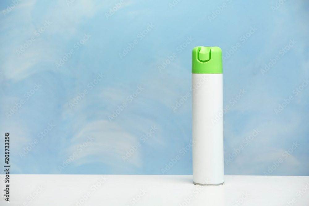 Spray air freshener on table against color background Spray air freshener on table against color background