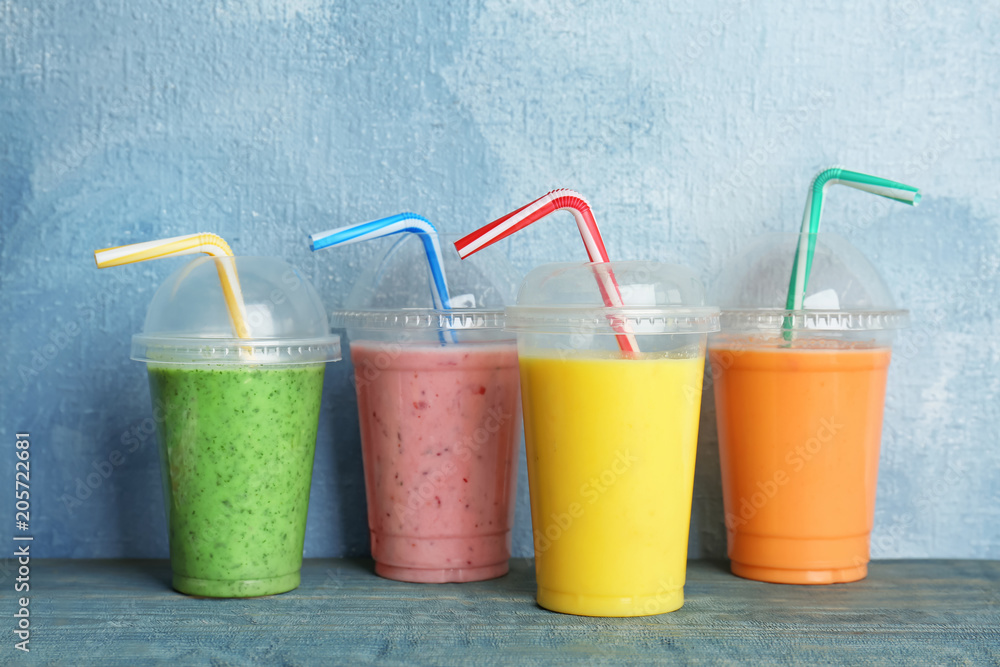 Plastic cups with delicious detox smoothies on table Plastic cups with delicious detox smoothies on table