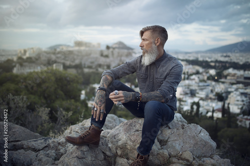 Porträt eines bärtigen Mannes, der in Athen auf dem Berg gegenüber dem Akropolis sitzt und den Sonnenuntergang genießt
