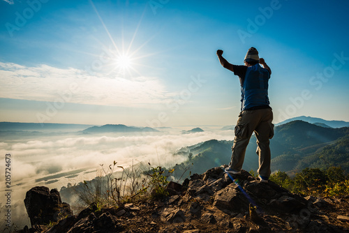 Silhouette man standing on top of the mountain watching the sun rise with fog