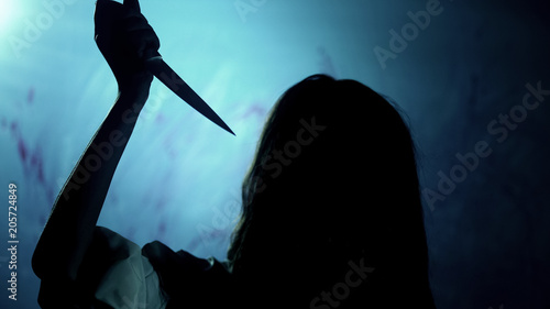 Bloody dark-haired murderer stabbing victim with knife, darkness and horror