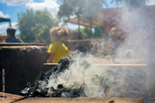 Horizontal View of a Barbecue Burning with Smog on Blur People Background