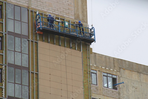 Facing multi-storey building - builders working on a steep wall