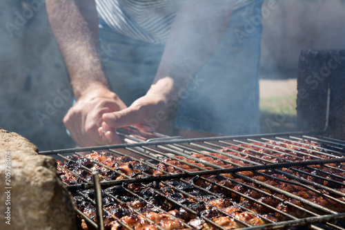 Horizontal View of A Man Holding a Grill Burning on Barbecue Full of Sausage and Italian Food Called Fegatini