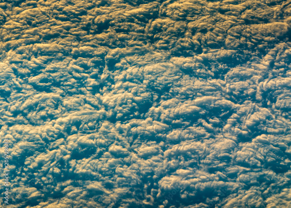 Fototapeta premium Flight from Europe to South Asia. View under a passenger aircraft. Below the thick clouds illuminated by the sun. Horizontal view