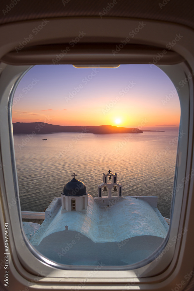 Fototapeta premium Amazing sunset at Panagia Theoskepasti, on the Skaros rock at Imerovigli, Santorini, Greece through a frame of plane window.