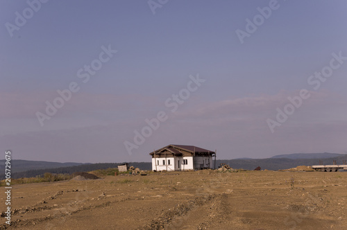 Lonely white forgotten building on the sand mountain. Deep calm blue sky with tints of purple. Ural landscapes. Brown colors. Like a desert