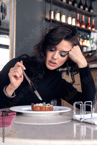 woman with dark curly hair in elegant dress sitting in elegant restaurant