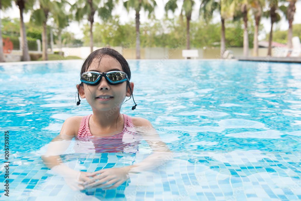 Portrait of Asian teen girl with goggles playing in swimming pool