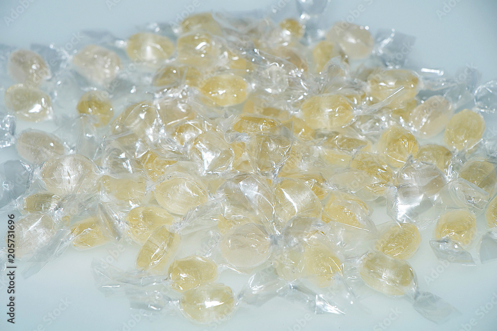 Yellow candy in a transparent wrapper on a white table Yellow candy in a transparent wrapper on a white table