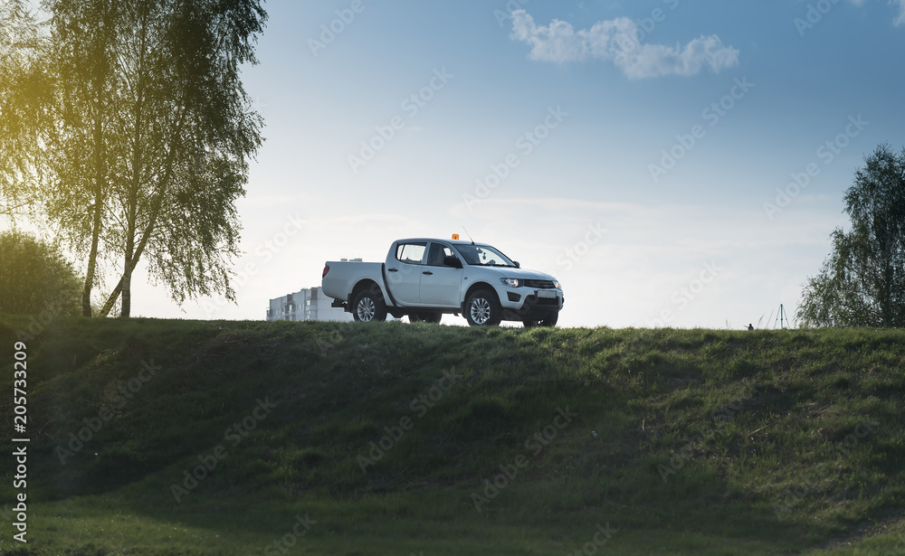 adventure car pick up find on a green grass hill off road way under the summer sunset - obrazy, fototapety, plakaty 