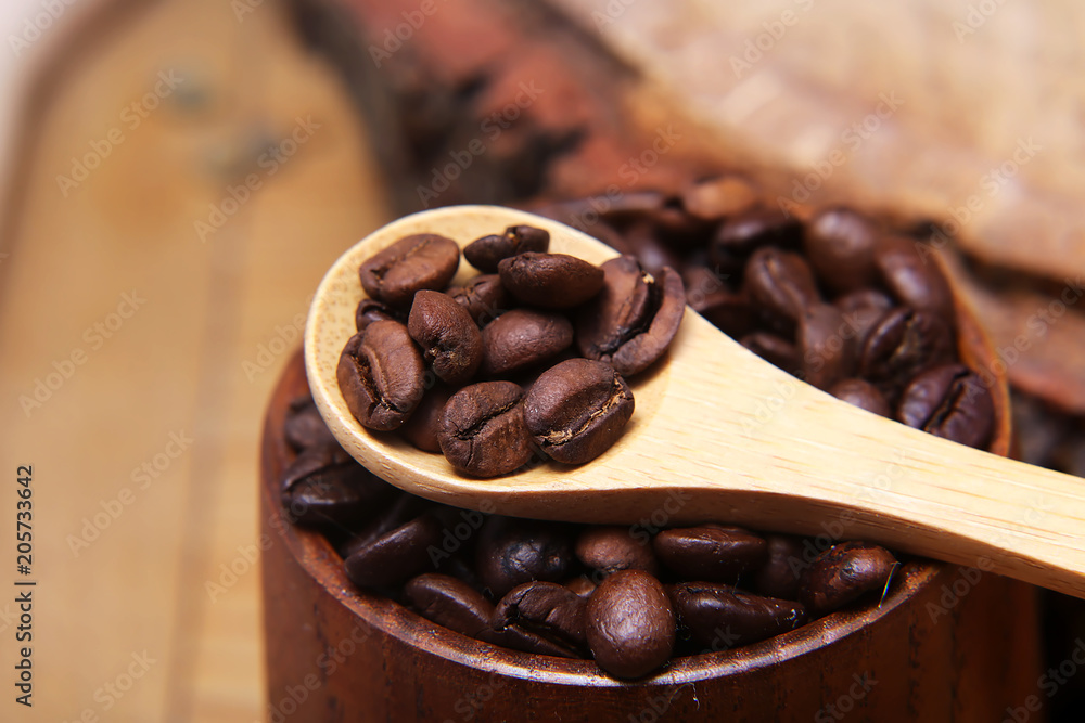 Fototapeta premium close-up various kinds of coffee beans scattered on a wooden background, ground coffee, wooden spoon empty space for text, macro, set